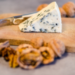 Tranche de Roquefort sur planche à découper avec couteau Laguiole moderne et noix